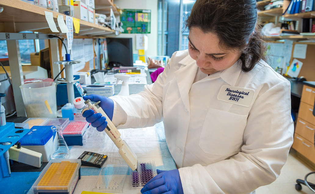 Female researcher pipetting in lab.