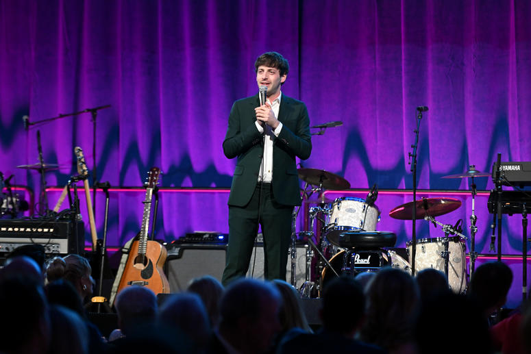 Comedian Alex Edelman performing onstage. 