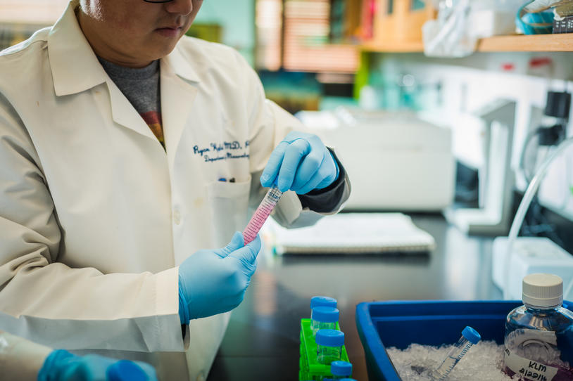 Scientist in lab holding up blood sample