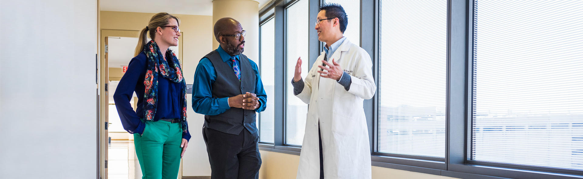 Doctor talking with two patients in the hallway at his office.