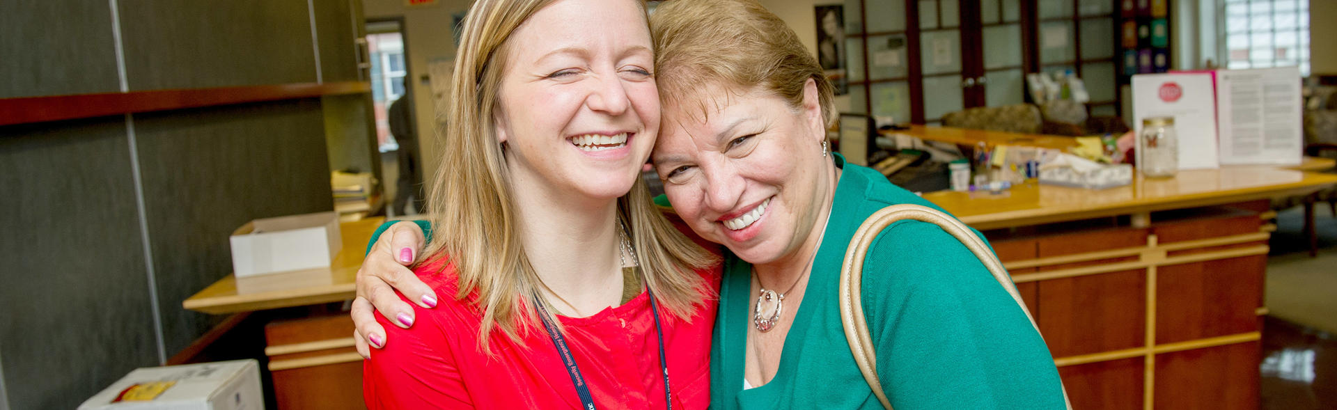 Two females smiling and embracing in the doctor's office.