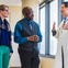 Doctor talking with two patients in the hallway at his office.