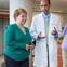 Woman wearing green shirt walking with her male physician through the doctor's office.